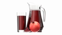 Jug and glass with pomegranate juice and fruit